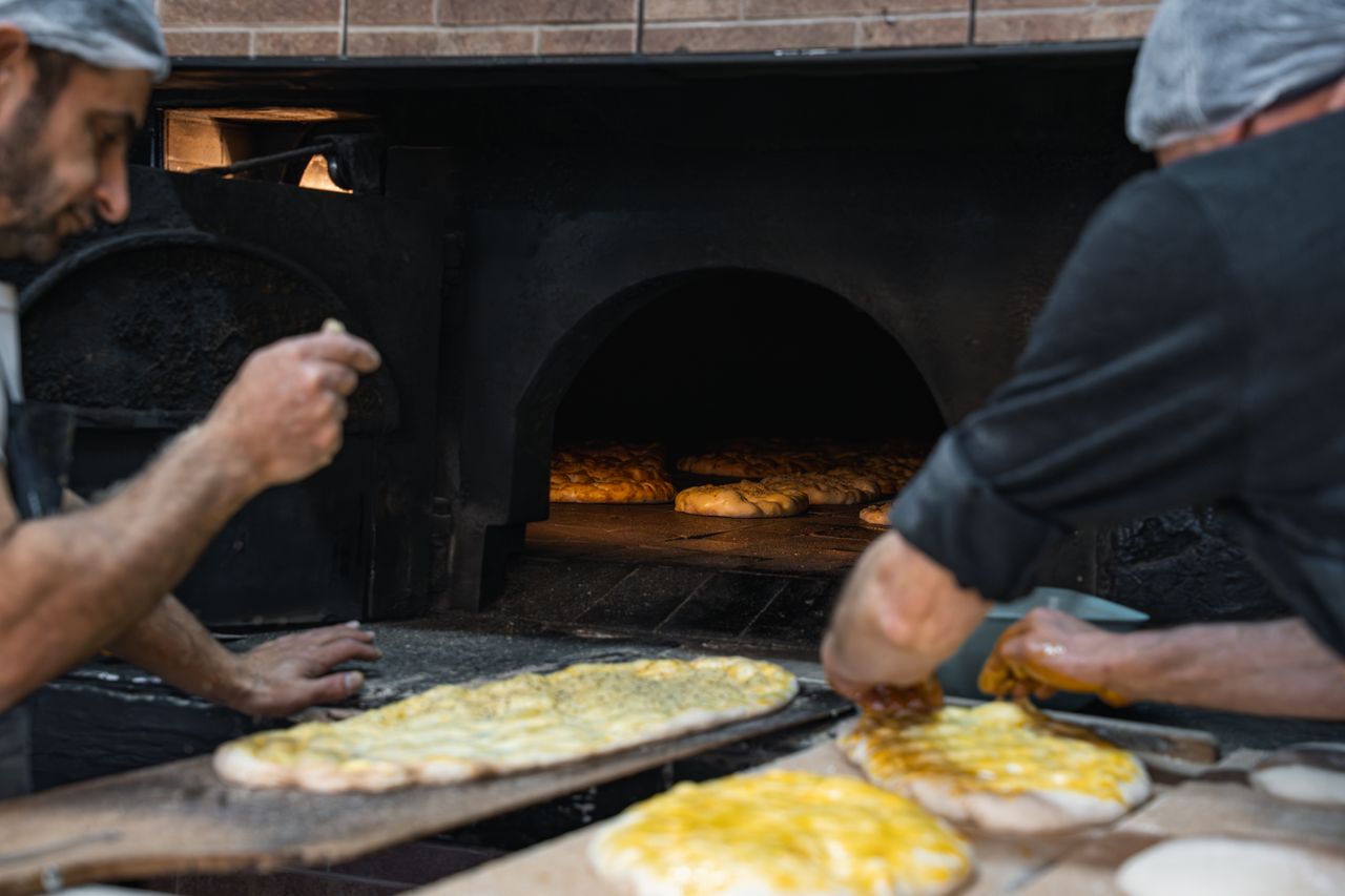 Artisan bakers work together to bake bread in a traditional stone oven, showcasing craftsmanship.